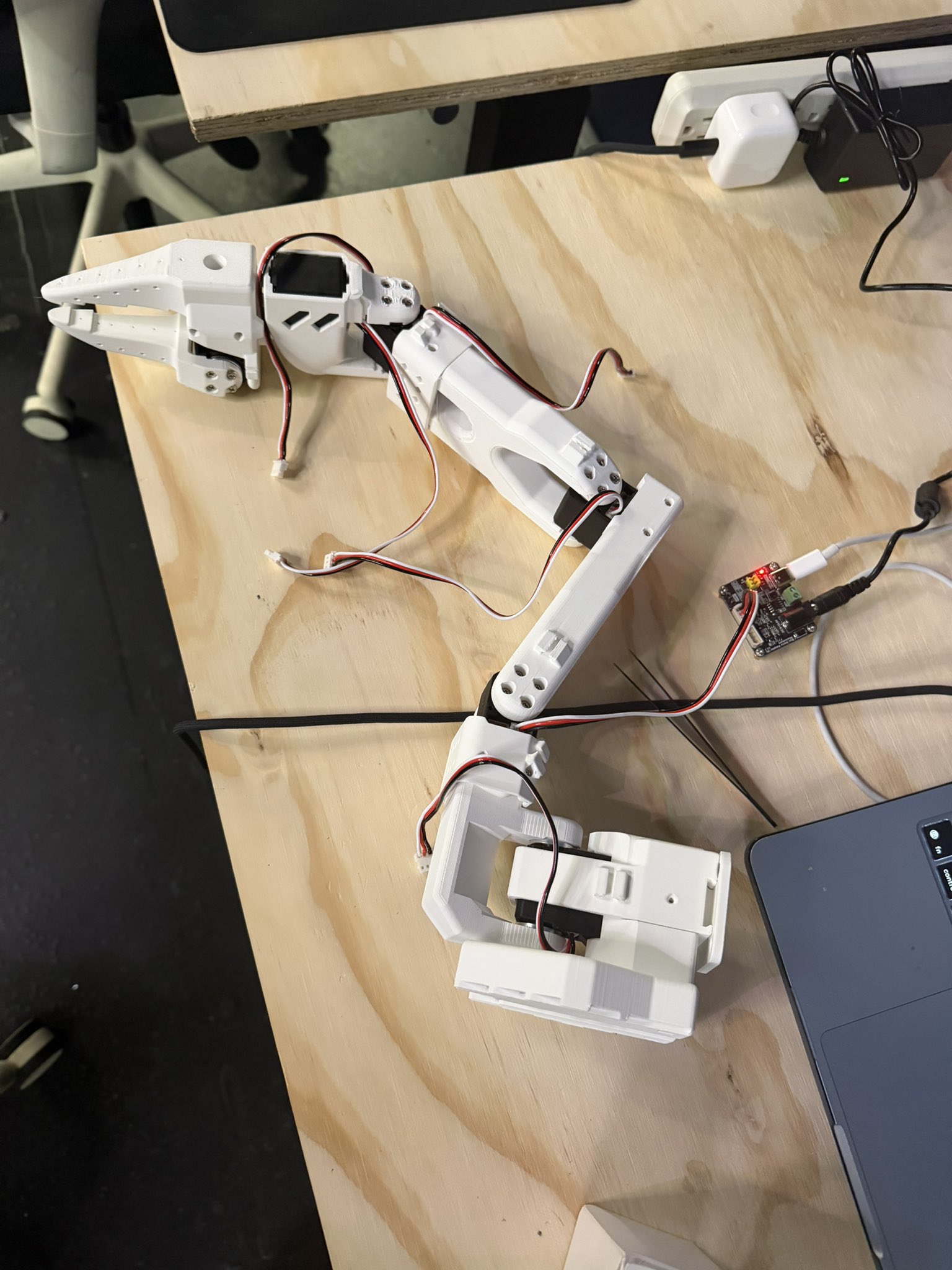 The SO-101 arm laid out flat on a plywood desk